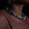 Side view of a woman wearing an Aji XL chunky chain necklace with large, textured silver links, captured in dim lighting.