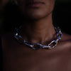 A woman wearing an Aji XL silver thick chain necklace with large, textured links in low lighting, emphasizing the necklace’s unique design.