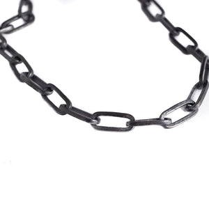 Close-up of a big black chain with rectangular links arranged loosely in a curve against a white background.