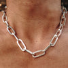 Close-up of a sterling silver big chain necklace with rectangular links resting on a person's bare neck.