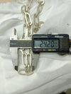 A digital caliper measuring the width of a chunky chain necklace, displaying 24.20 mm, placed on a white fabric background.