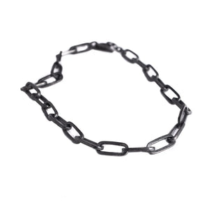 Isolated large chunky chain with rectangular black links arranged in a loose loop against a white background.