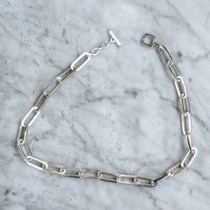 Sterling silver chunky chain necklace with rectangular links and a toggle clasp, placed on a marble surface.