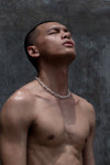 Shirtless man with a shaved head wears the Ula bold chunky chain necklace, standing against a textured background with his head tilted back.