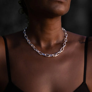 Woman wearing the Ula silver thick chain necklace, photographed against a dark background.