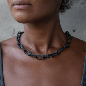 Close-up of a person wearing the Ula X thick chain, a bold and textured chain necklace in oxidized silver designed for a statement look.