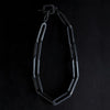 XL black chunky chain necklace with large rectangular links and a square clasp, arranged in a loop against a dark background.